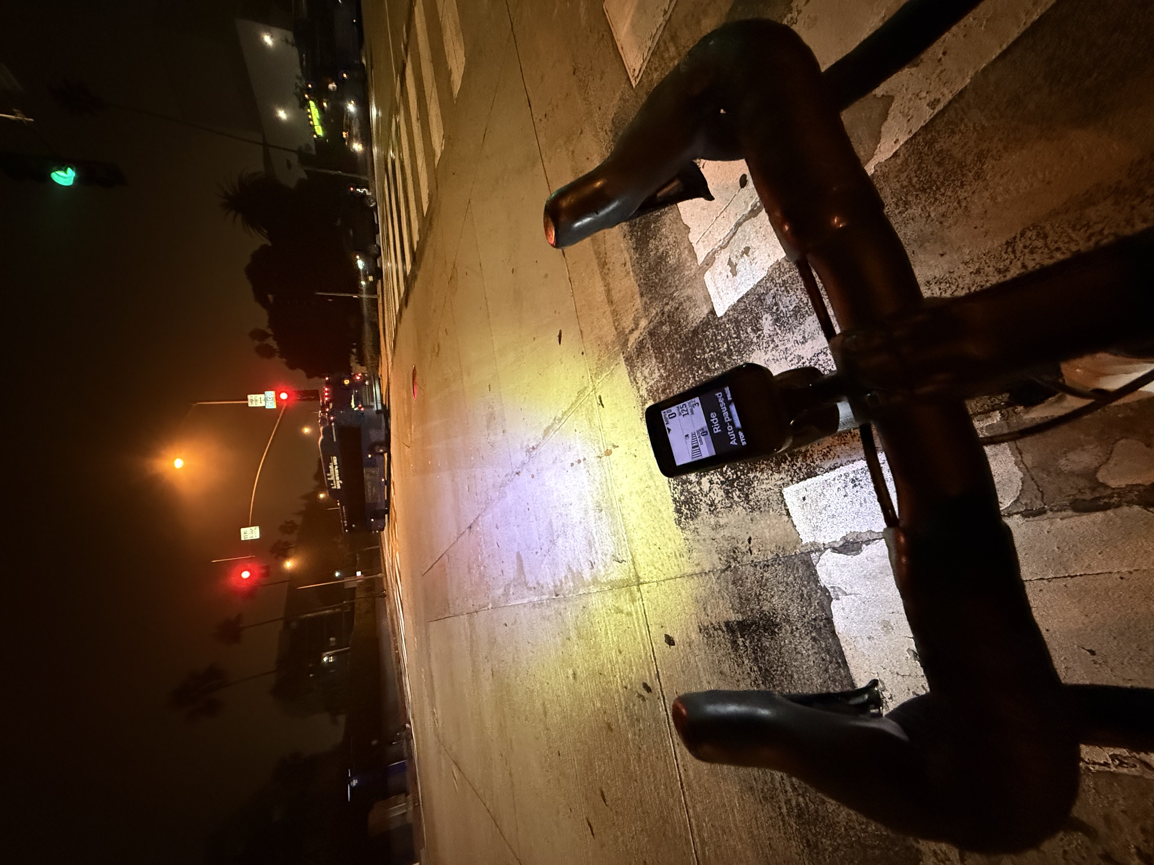 View from a bike at a Santa Monica intersection at night, daytime running light pattern on the road, bus crossing ahead