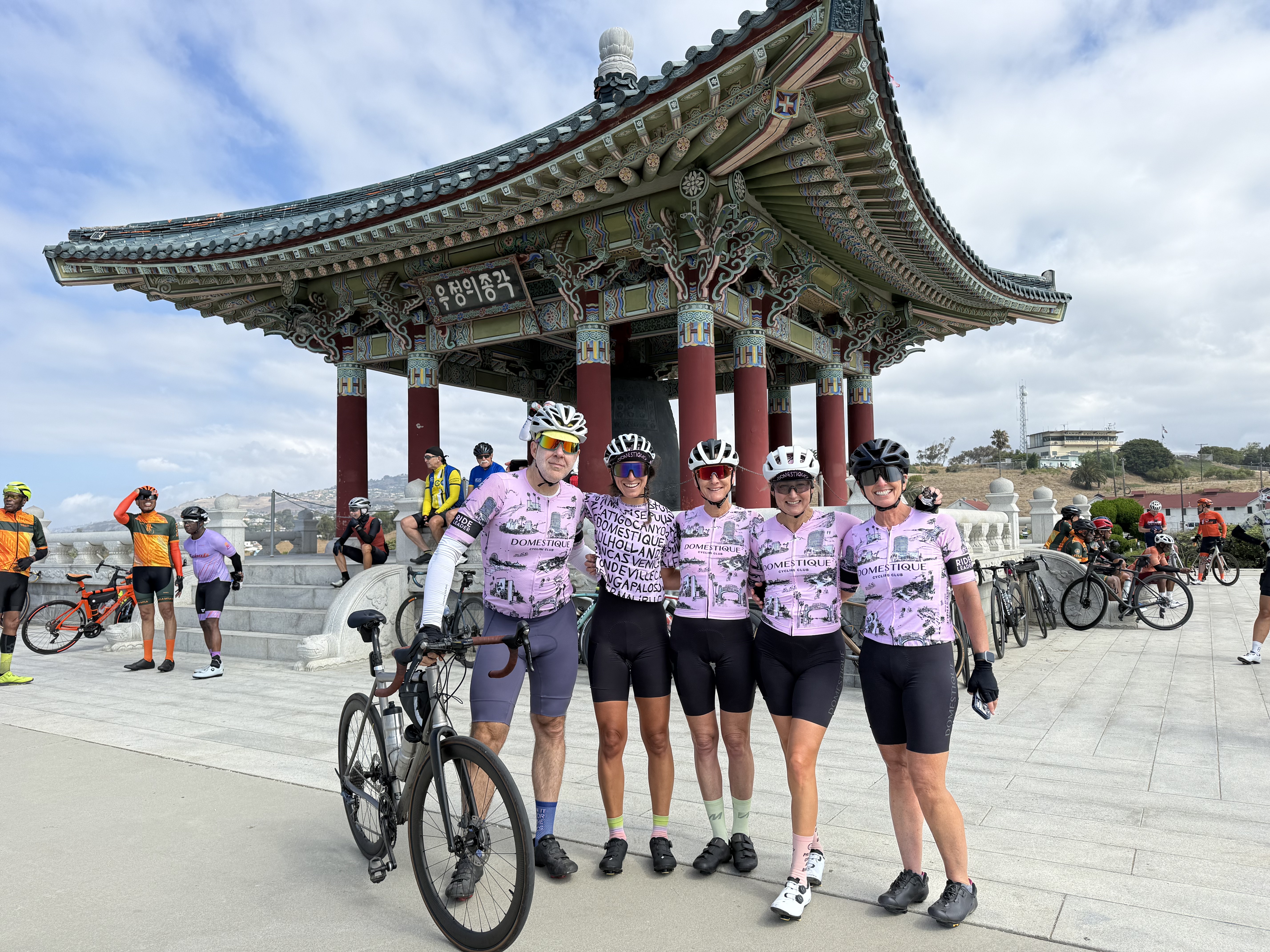 Five DCC members in pink club kit standing in front of the Korean Bell of Friendship in San Pedro