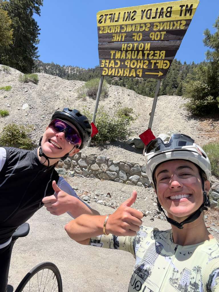 Two smiling DCC riders giving thumbs up below the Mt Baldy Ski Lifts sign